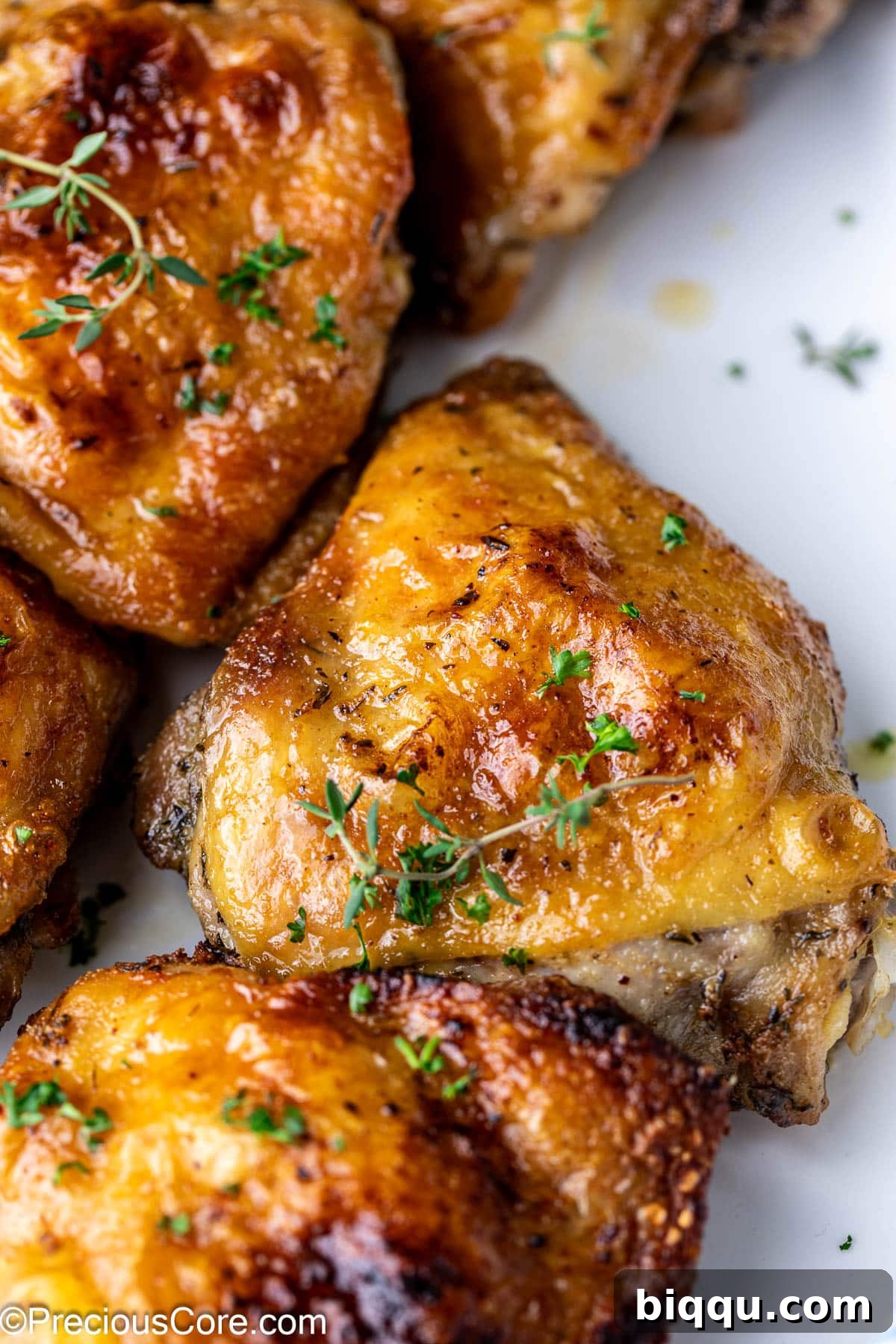 Zoomed-in shot of a perfectly cooked chicken thigh, elegantly garnished with a sprig of fresh thyme.