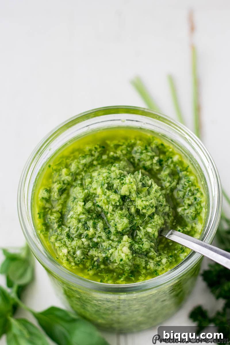A jar of homemade green seasoning, a vibrant green sauce ready to infuse meals with flavor.