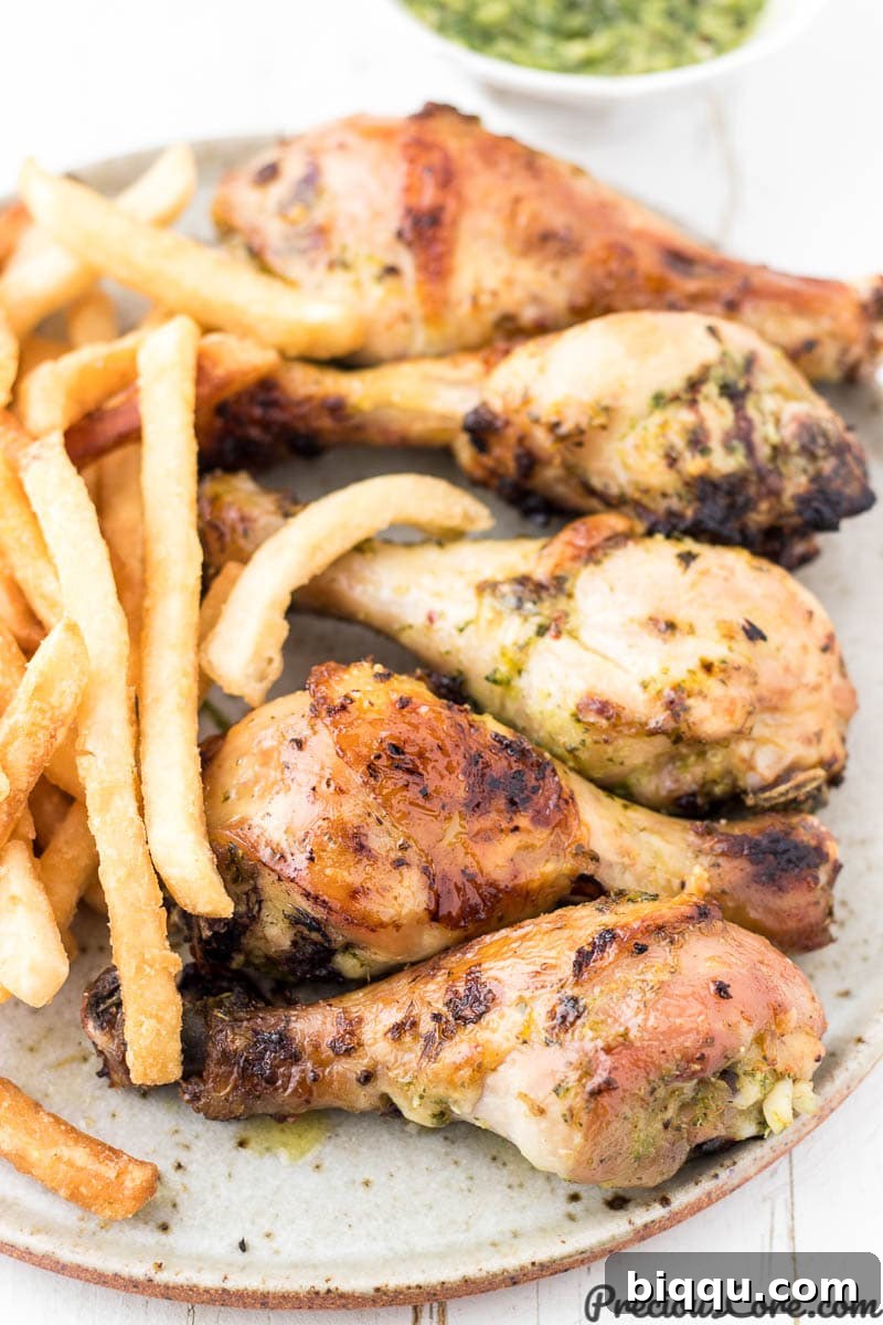 A plate of crispy chicken and golden fries, with a small bowl of green sauce on the side for dipping.