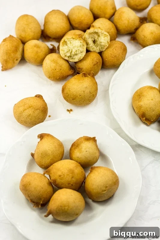 Cameroon doughnuts on two white plates and parchment paper, showcasing their golden-brown perfection.