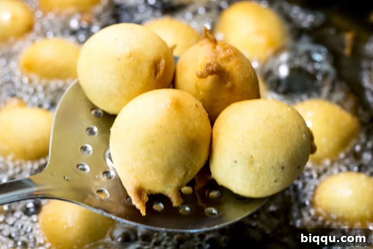 Frying spoon lifting some golden Cameroon doughnuts from the oil.
