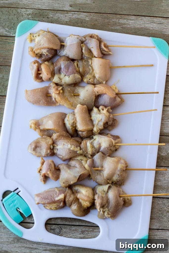 Raw, seasoned chicken pieces neatly threaded onto skewers, ready for cooking