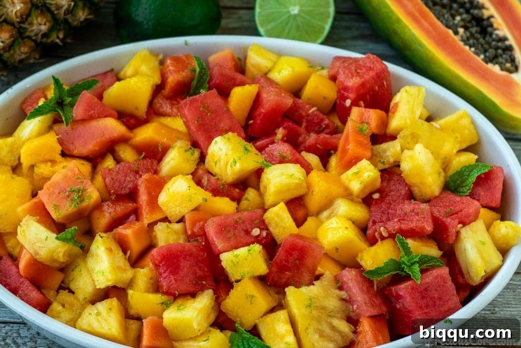 A panoramic view of a beautifully prepared tropical fruit salad in a clear glass bowl, showcasing vibrant colors and enticing textures.