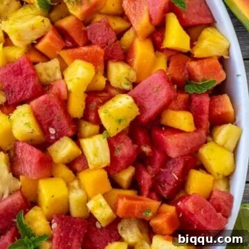 Tropical fruit salad in a serving bowl, garnished with mint.