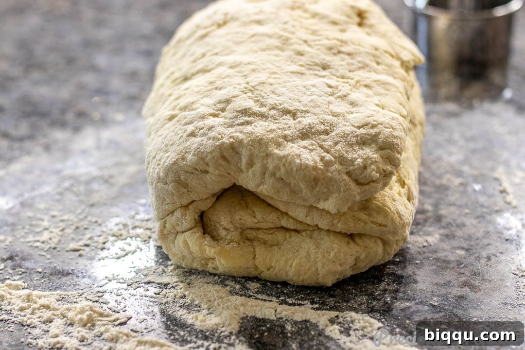 Biscuit dough being folded in thirds to create flaky layers.