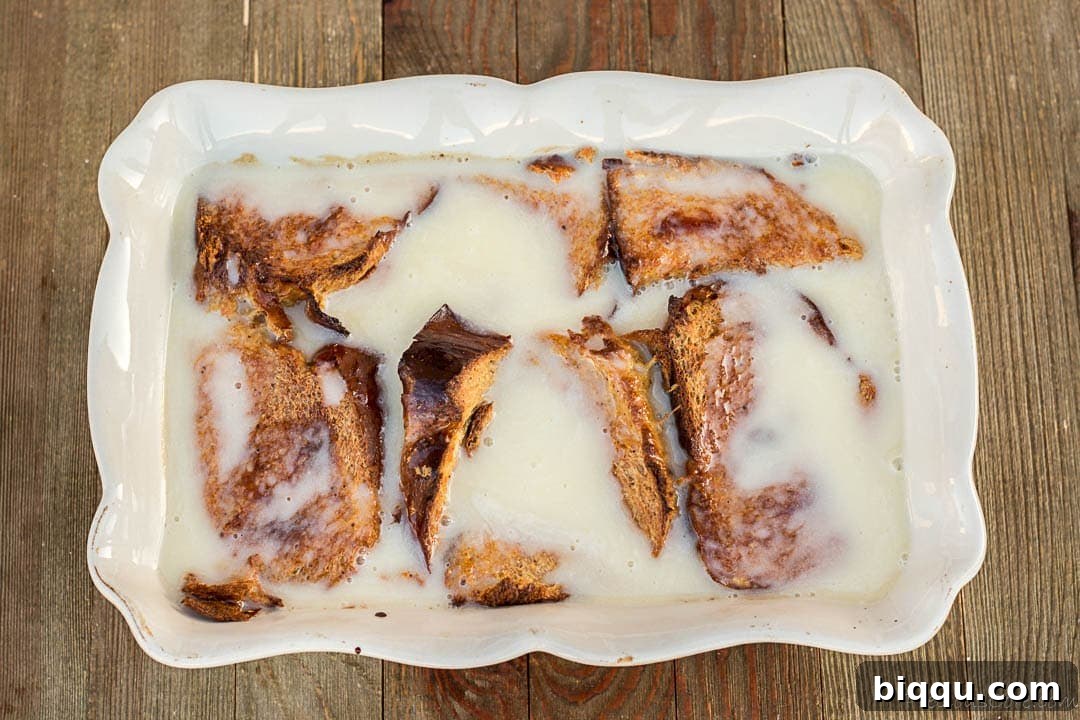Close-up shot of warm bread pudding generously covered in creamy, golden bread pudding sauce, emphasizing its luxurious texture and appeal.