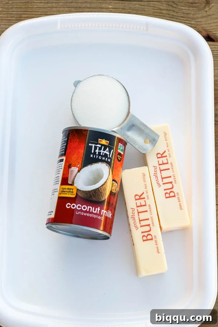 The three essential ingredients for making bread pudding sauce: a can of unsweetened coconut milk, a stick of unsalted butter, and a bowl of granulated sugar.
