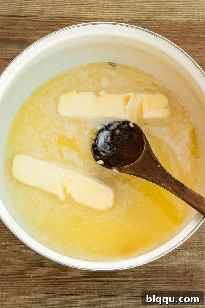 Unsalted butter and granulated sugar melting together in a saucepan on a stovetop, forming a clear, liquid mixture as the base for the sauce.
