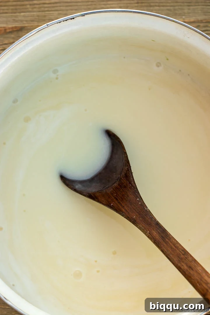 Creamy bread pudding sauce with coconut milk simmering gently in a pot, showing a smooth, consistent texture and rich color.
