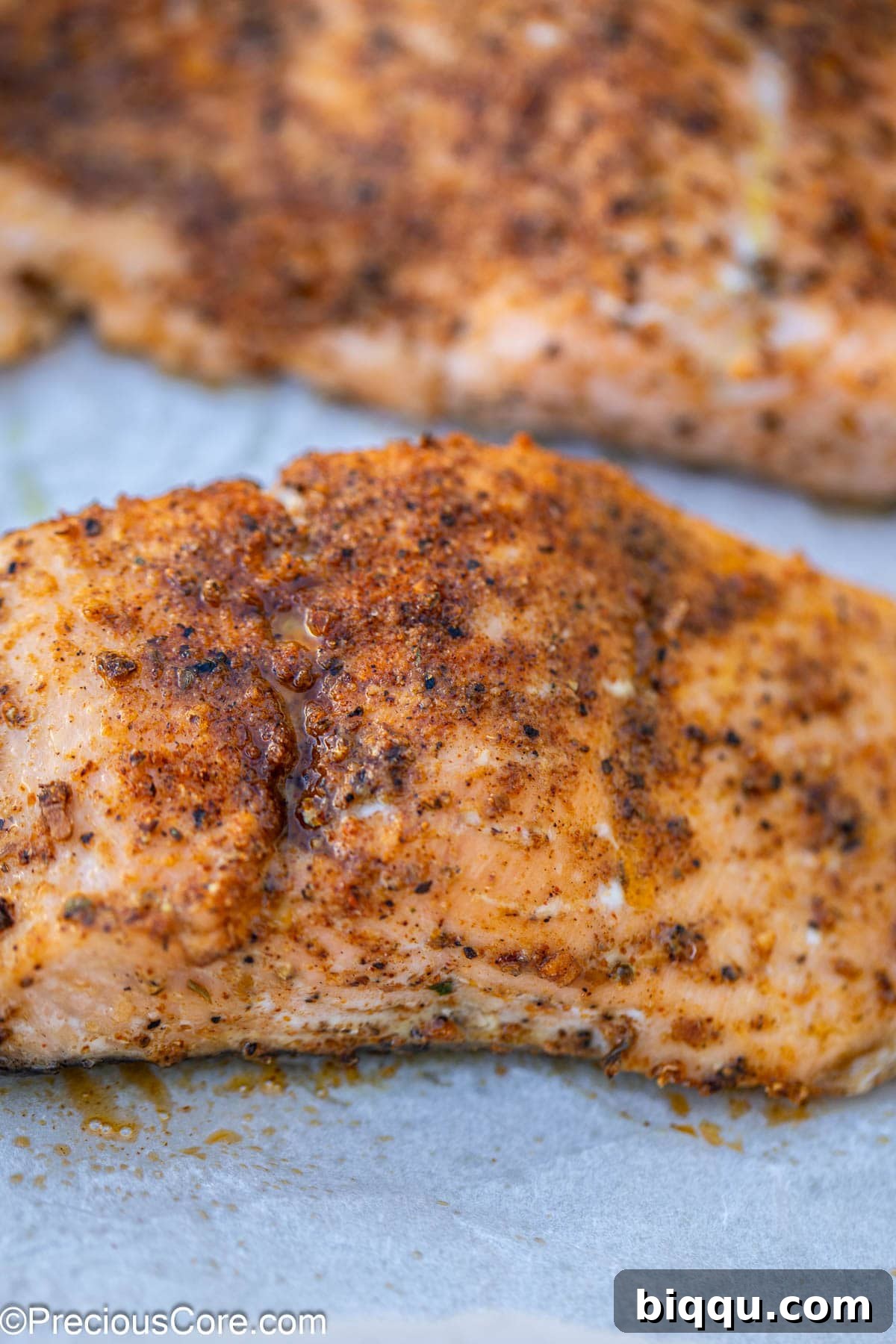 Close up shot of baked salmon, showcasing its crispy seasoning and tender interior.