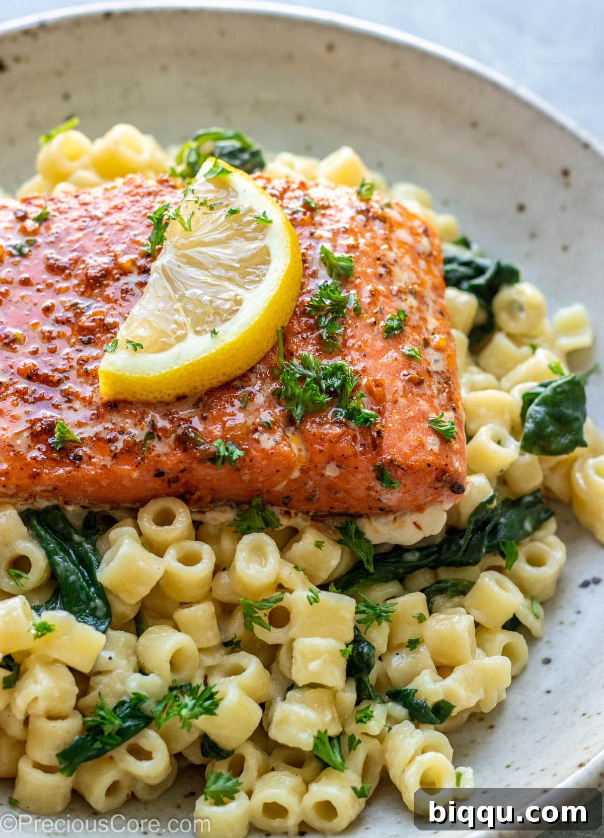 Cajun Salmon served over a bed of pasta in a white dish, garnished with fresh herbs.