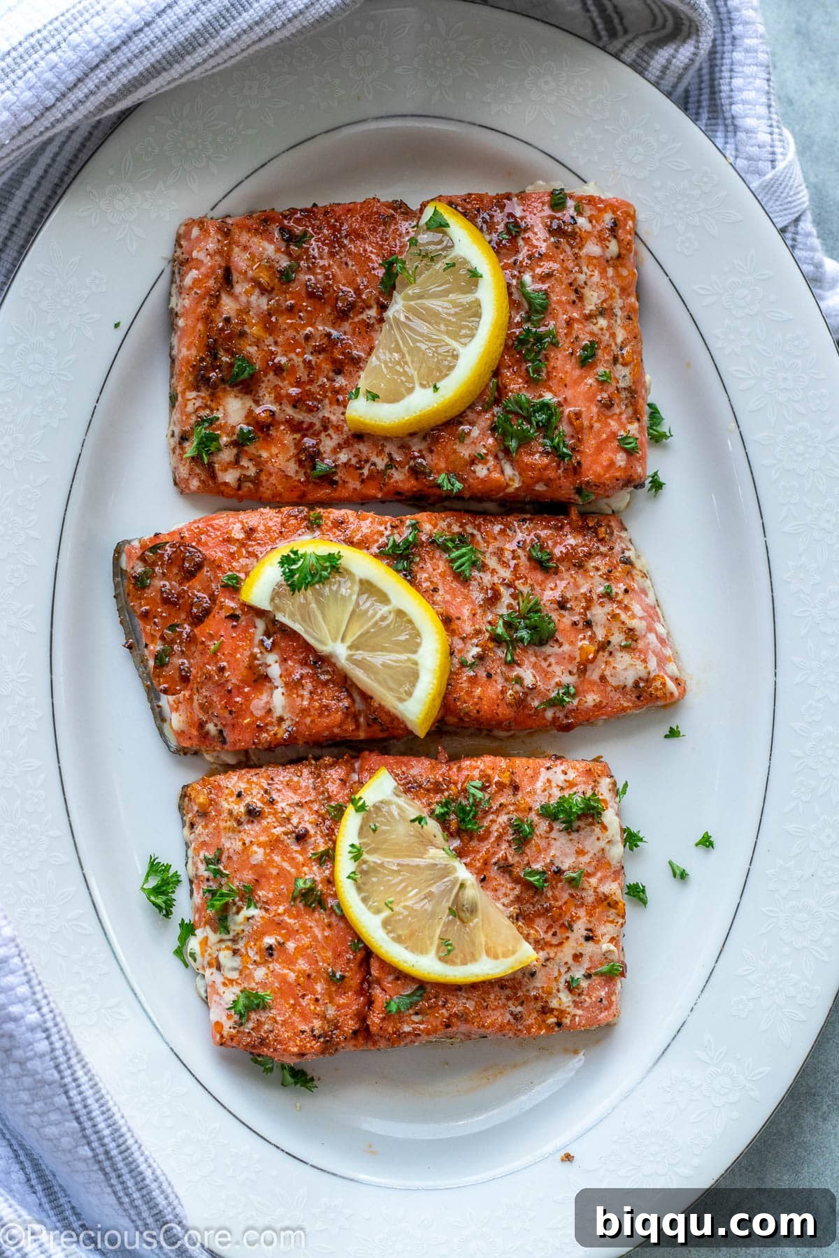 Baked Cajun Salmon on a white serving platter, garnished with fresh herbs.