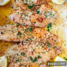 4 baked tilapia fillets in a pan.