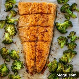 Large salmon fillet and roasted broccoli on a sheet pan