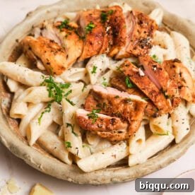 Creamy pasta in a bowl, topped with pan-seared chicken.
