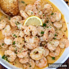 Crusty bread in a bowl of shrimp in white wine sauce.