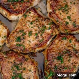 Pan seared boneless pork chops in a cast iron pan with butter underneath.