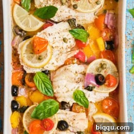 White fish fillets in a casserole dish baked with veggies.