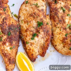 Thin sliced chicken breasts served with lemon wedges.