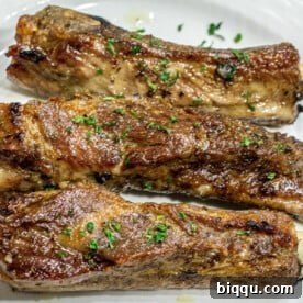 3 baked ribs on a white plate.