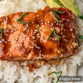 Teriyaki Salmon over rice with avocado slices in a bowl.