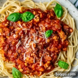 Spaghetti in a bowl topped with chicken Bolognese sauce.