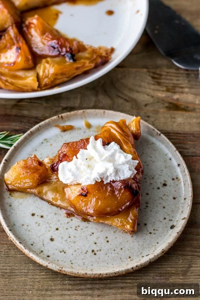 A slice of Tarte Tatin generously topped with luscious whipped cream, enhancing its appeal