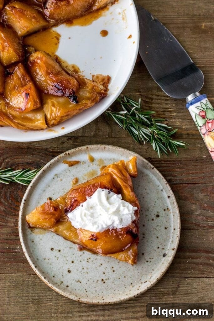 A delectable slice of Tarte Tatin topped with cream, with a large tart in the background