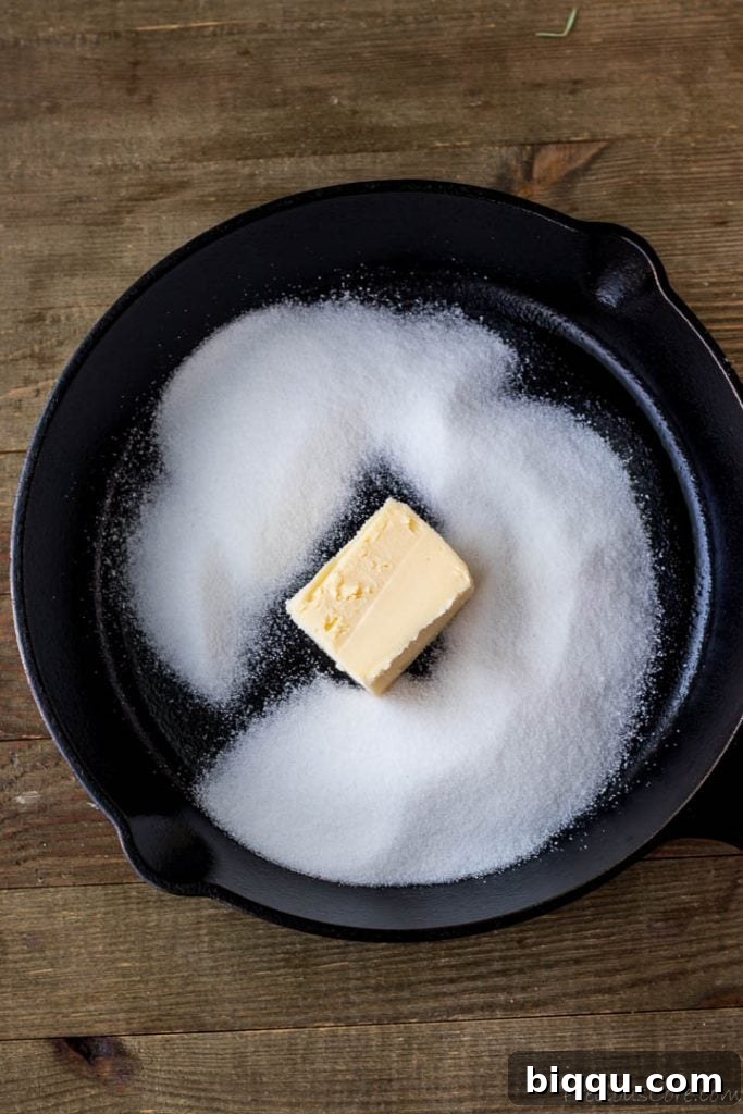Butter and sugar melting together in a cast-iron skillet, forming the caramel base