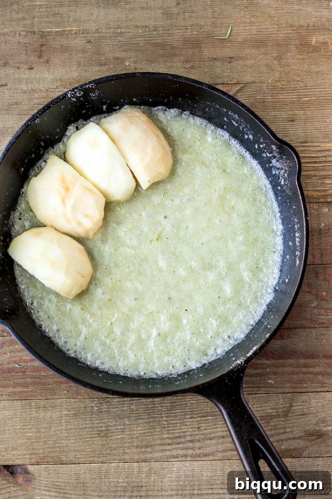 Apple slices carefully arranged over the bubbling caramel sauce in the skillet